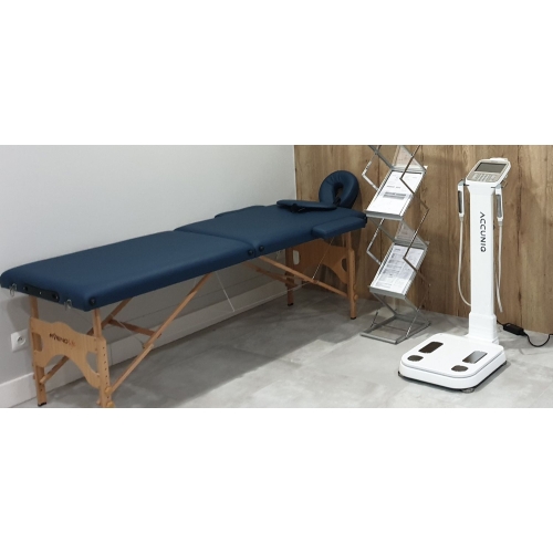 Analizator składu ciała ACCUNIQ BC380 opcja white w gabinecie obok łóżka terapeutycznego.