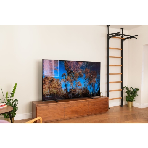 Drabinka BenchK 521B zamontowana w salonie, czarna rama i bukowe szczeble przy ścianie obok telewizora.