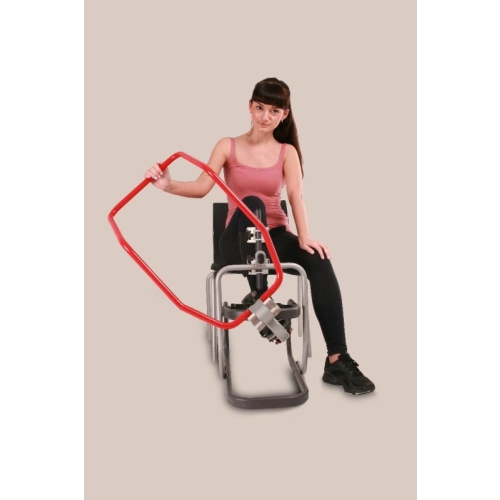 Pacjentka prezentuje regulowany uchwyt urządzenia DRACO do ćwiczeń kończyny dolnej.